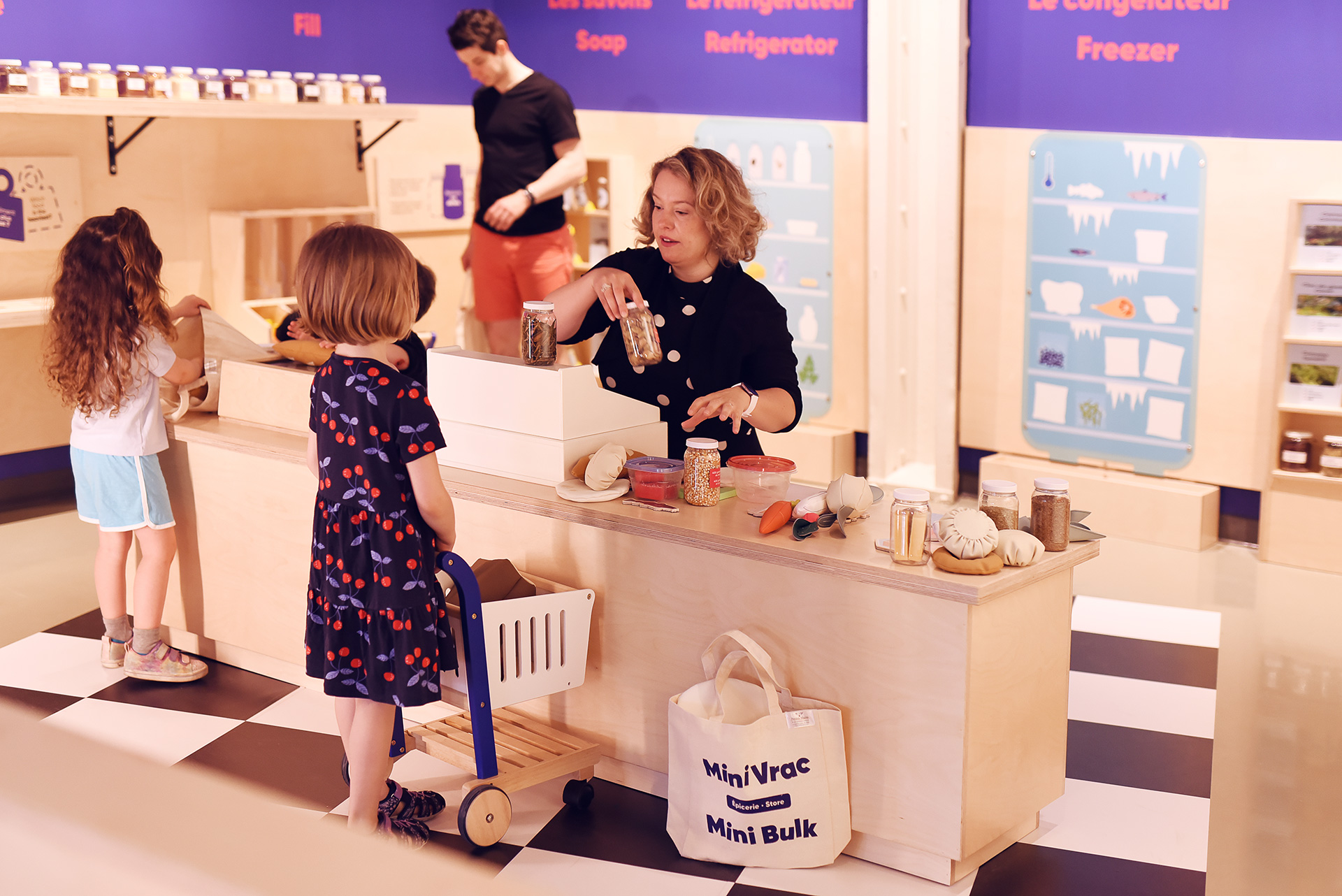Participants stand at a lowered countertop in a makeshift grocery store in the Mini Mondo exhibit