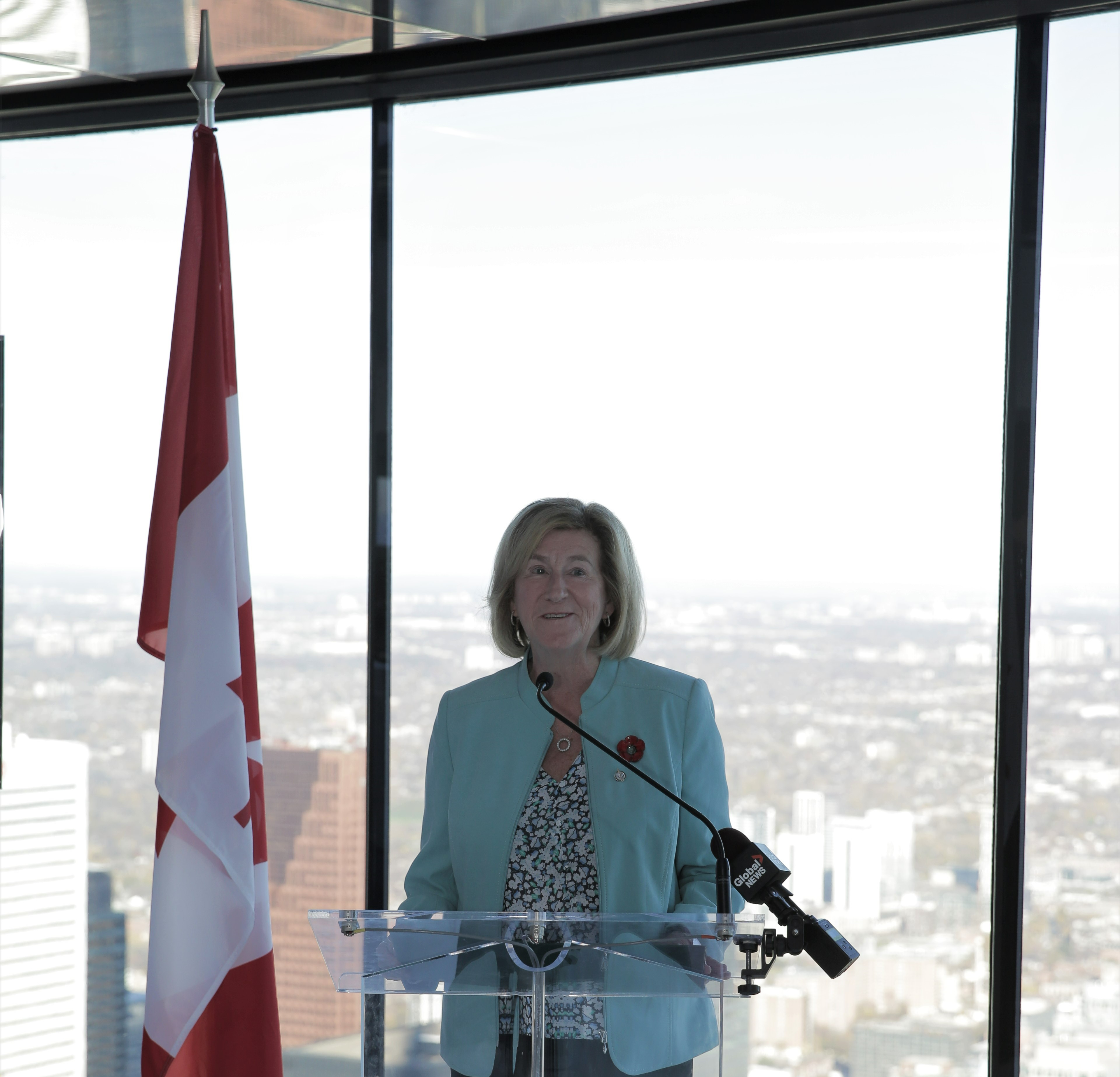 Flag and Minister Helena Jaczek at a podium