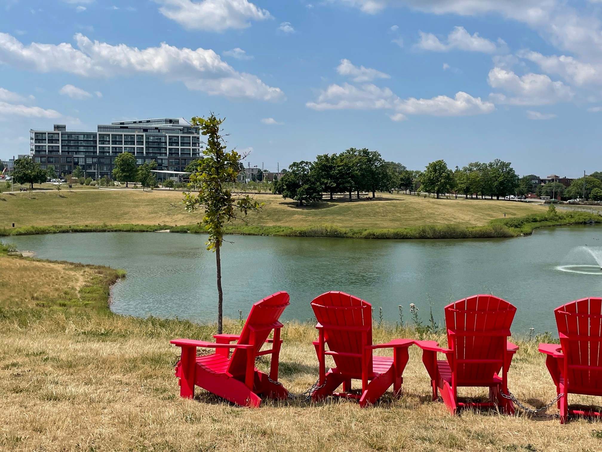 An image showing red Muskoka chairs facing a pond
