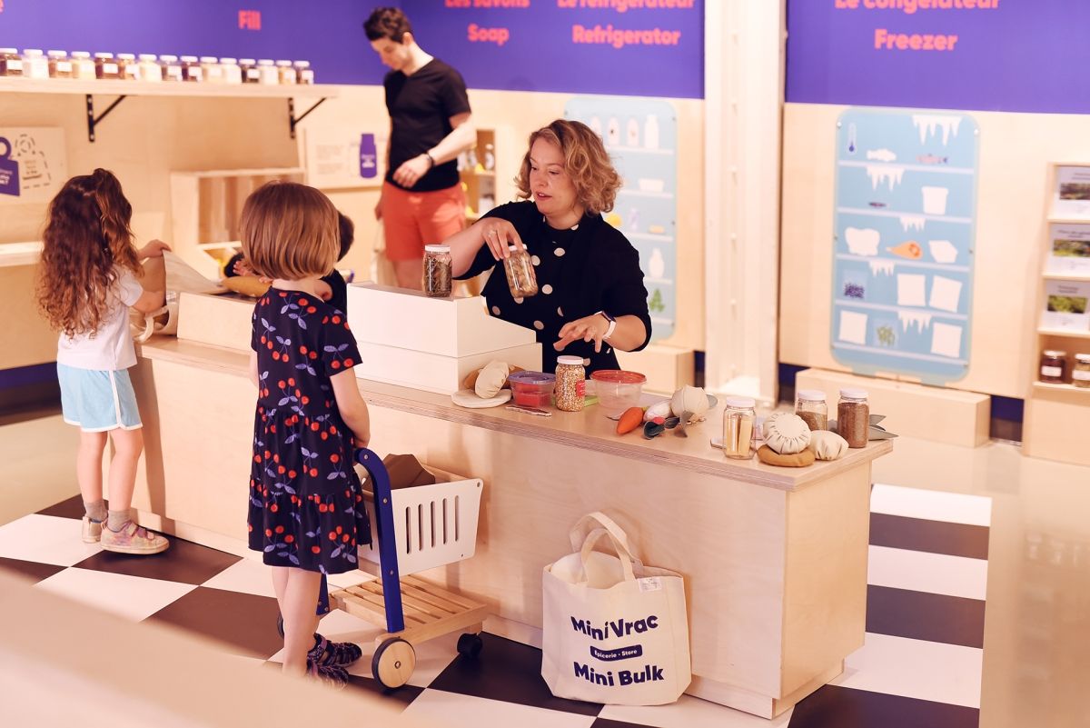 Participants stand at a lowered countertop in a makeshift grocery store in the Mini Mondo exhibit