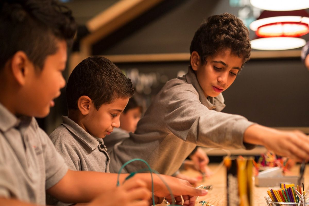 Three boys participate in an activity at the Montreal Science Centre