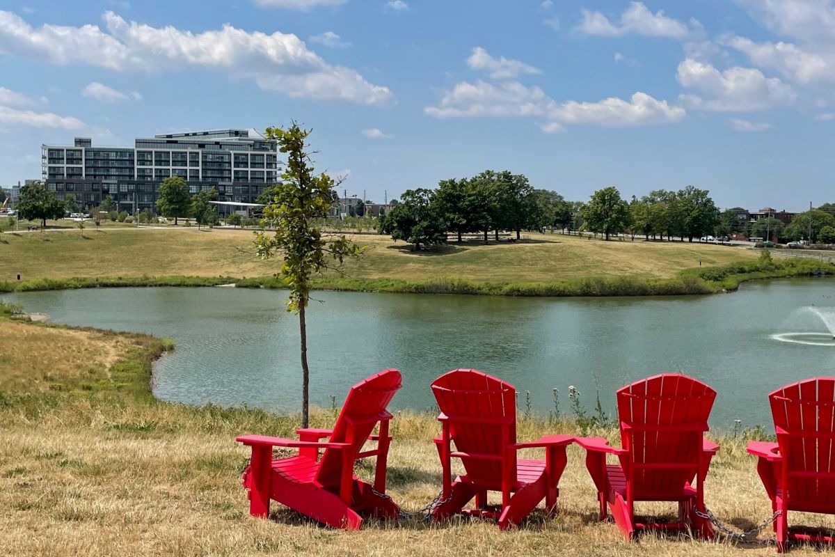 An image showing red Muskoka chairs facing a pond