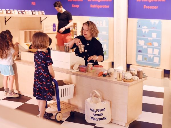 Participants stand at a lowered countertop in a makeshift grocery store in the Mini Mondo exhibit