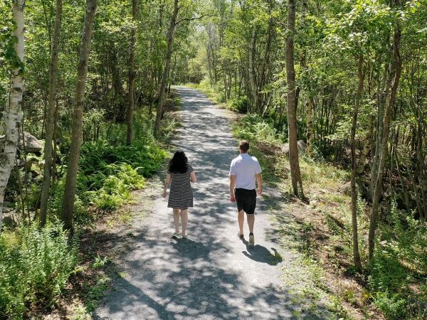Two people walk along a path surrounded by trees